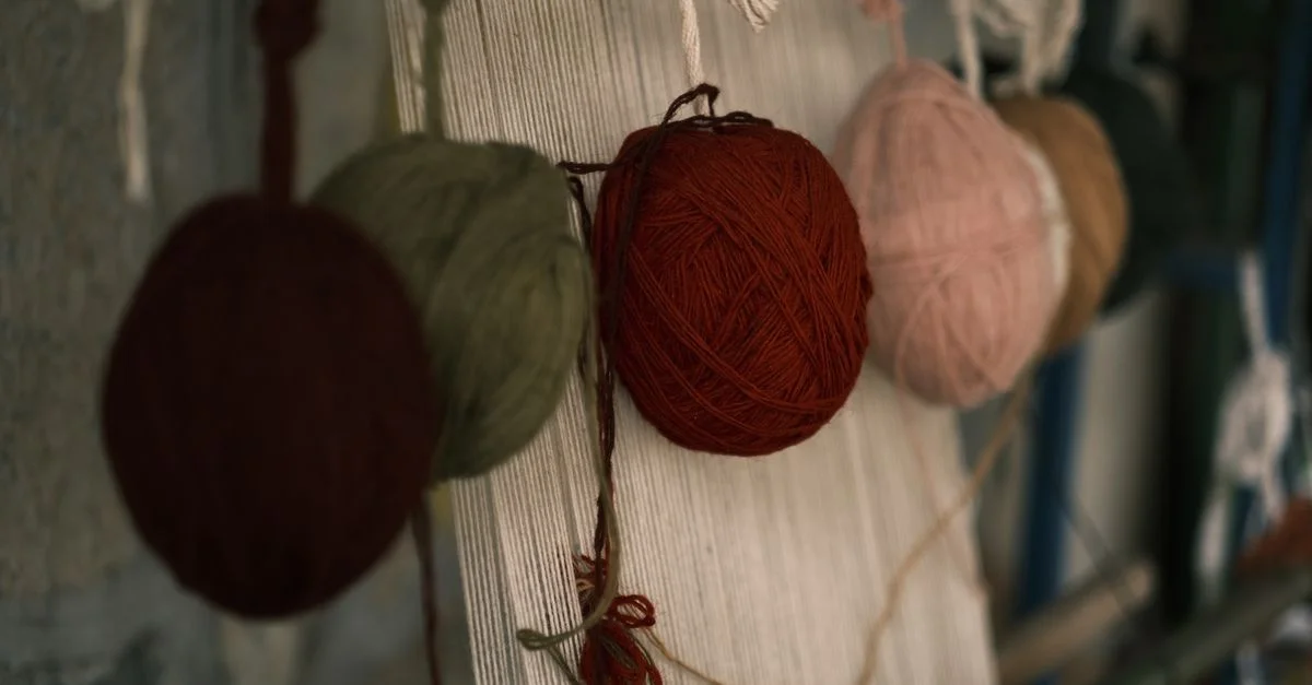 Des pelotes de laine vibrantes suspendues à un métier à tisser, mettant en valeur l'art textile et le savoir-faire.