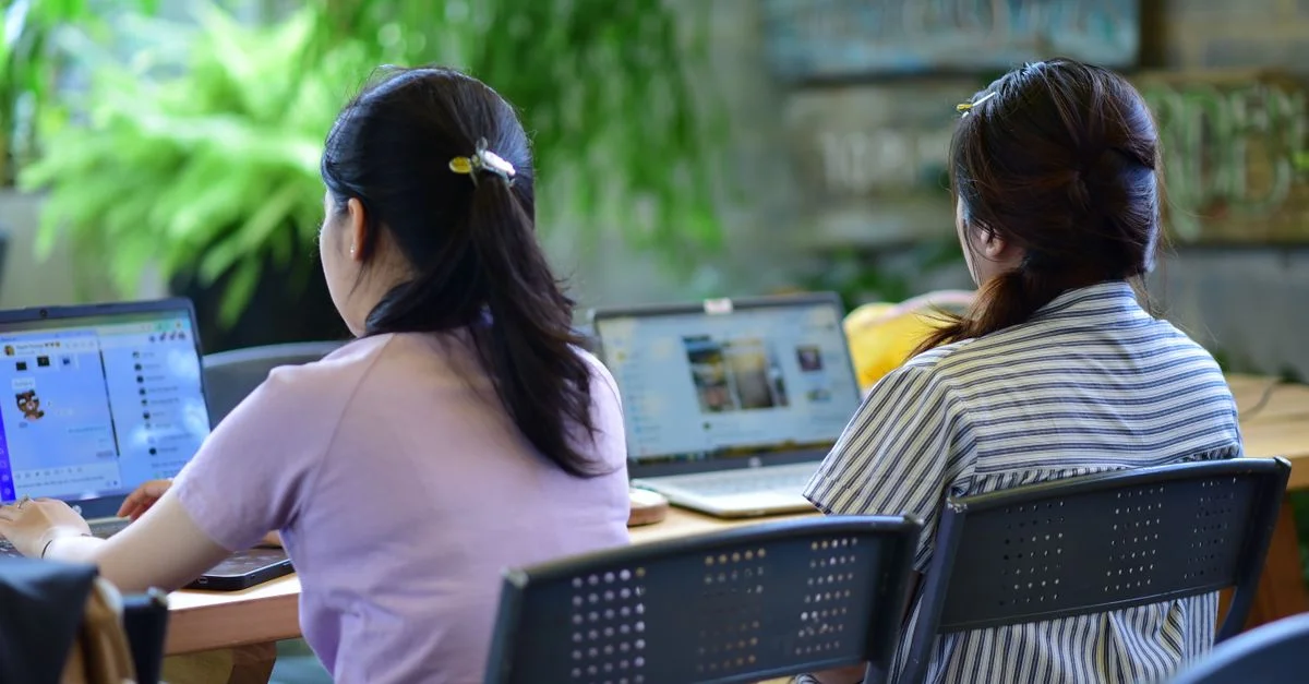Deux femmes travaillant sur des ordinateurs portables dans un espace de bureau moderne et écologique.