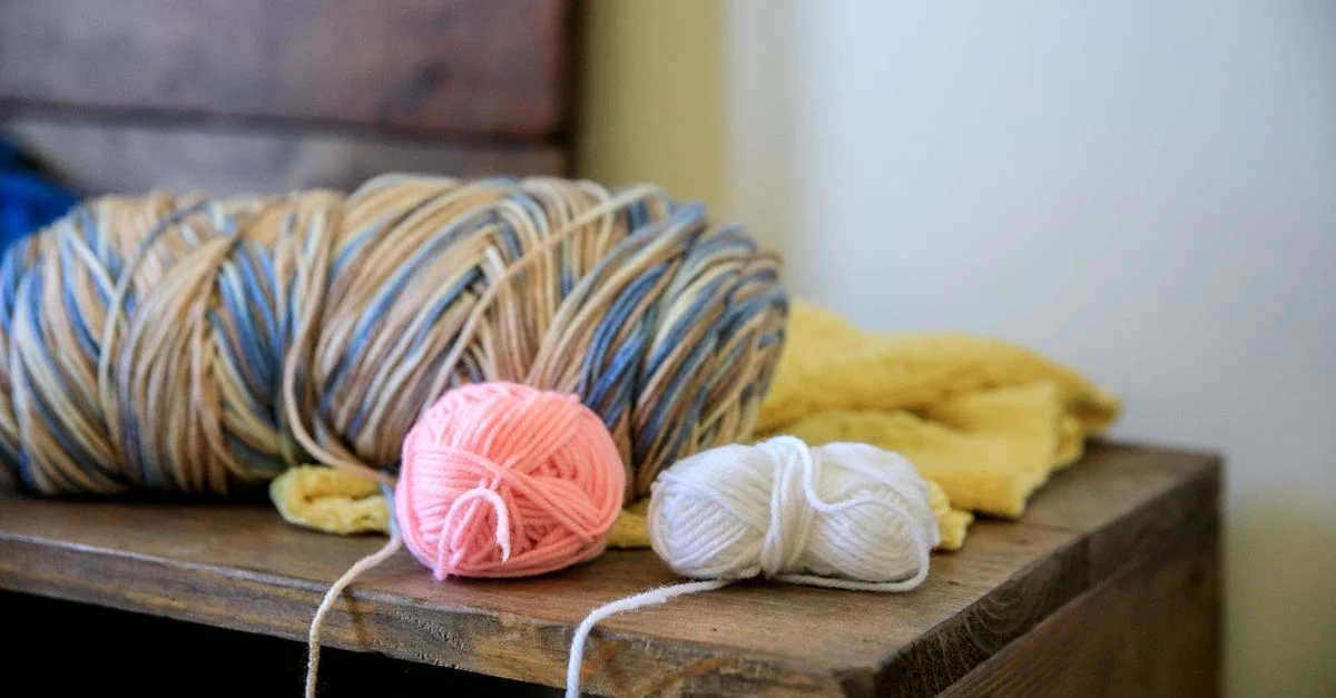 Gros plan de pelotes de laine colorées sur une table en bois, parfaites pour des projets de bricolage et de tricot.
