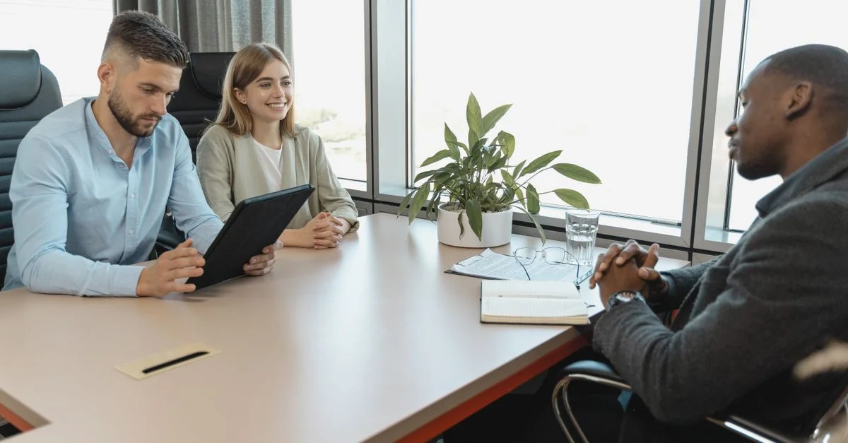 Un entretien d'affaires avec trois personnes dans une salle de bureau moderne, mettant en avant la collaboration.