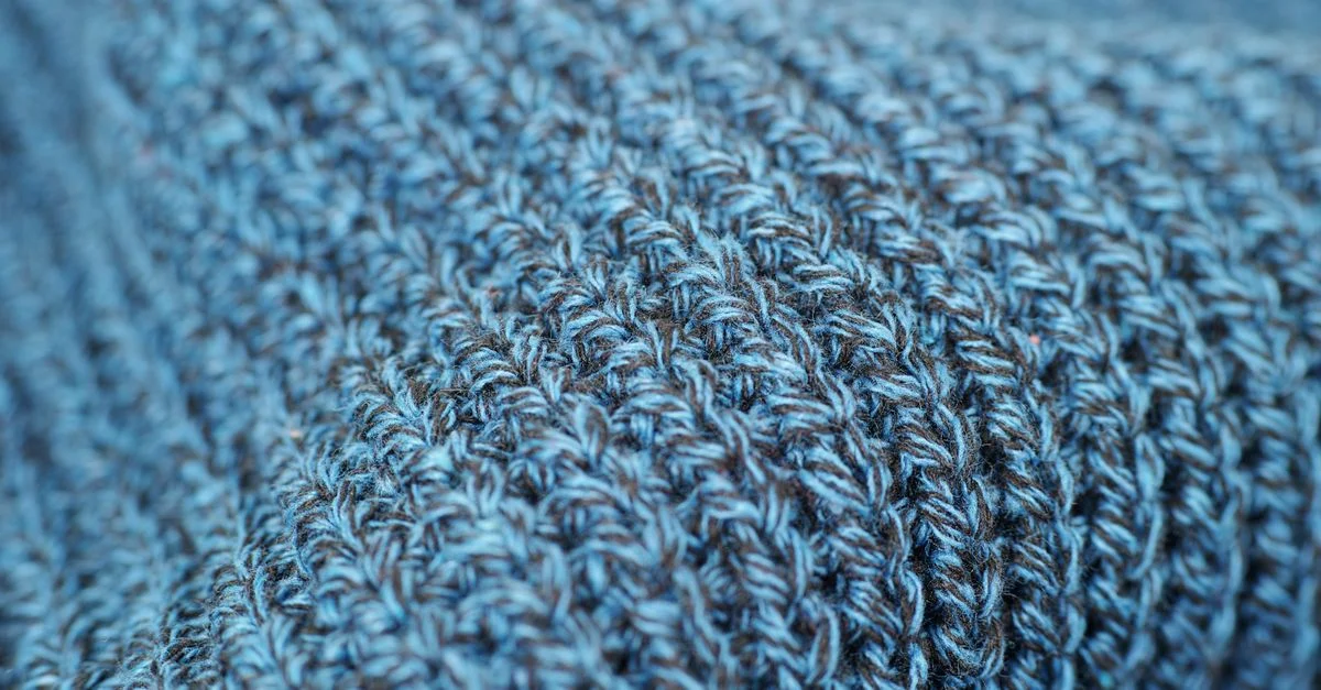 Prise de vue macro de tissu en laine bleu tricoté montrant un motif tissé et une texture intricats.