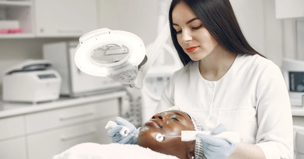 Un dermatologue applique un traitement de soins de la peau à un client dans un cadre de clinique.