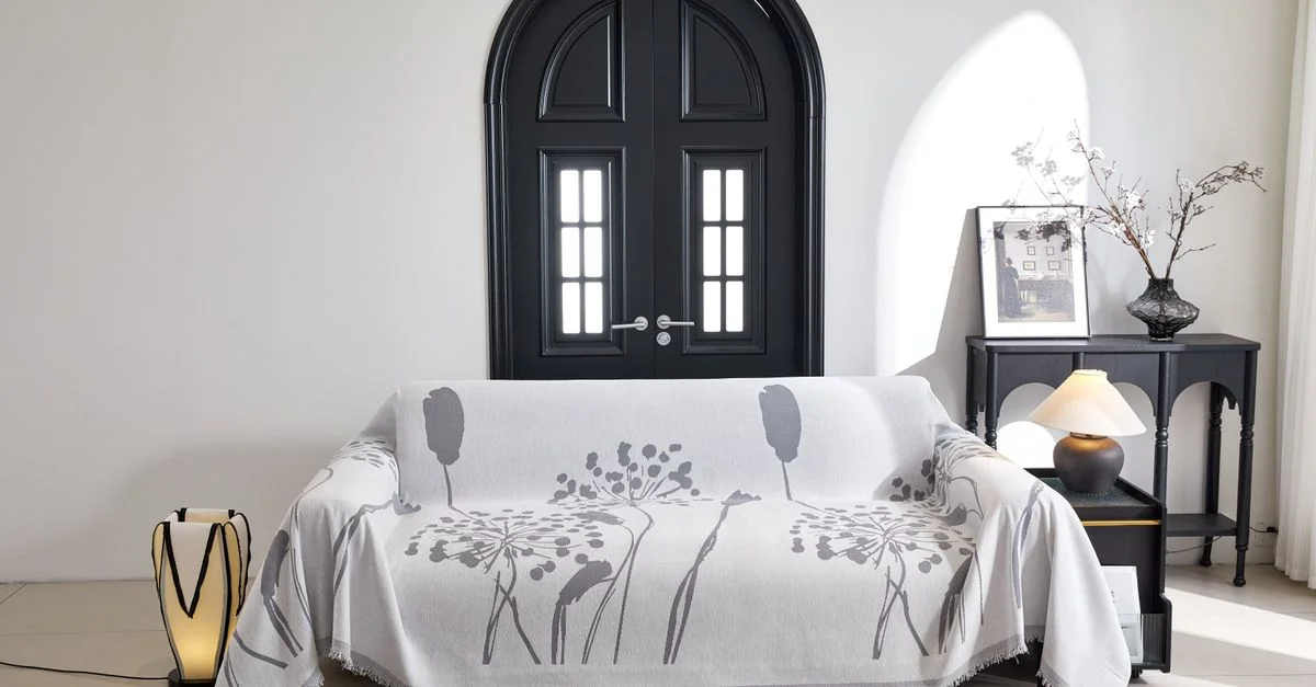 Salon contemporain avec une housse de canapé élégante, une décoration raffinée et un éclairage unique.